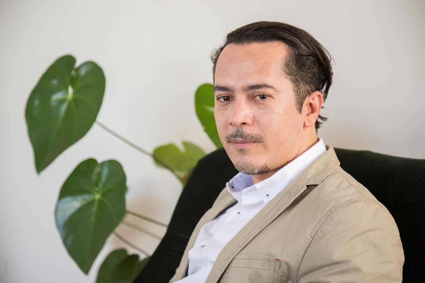 Sérgio Felix sentado numa poltrona, ao lado de uma planta